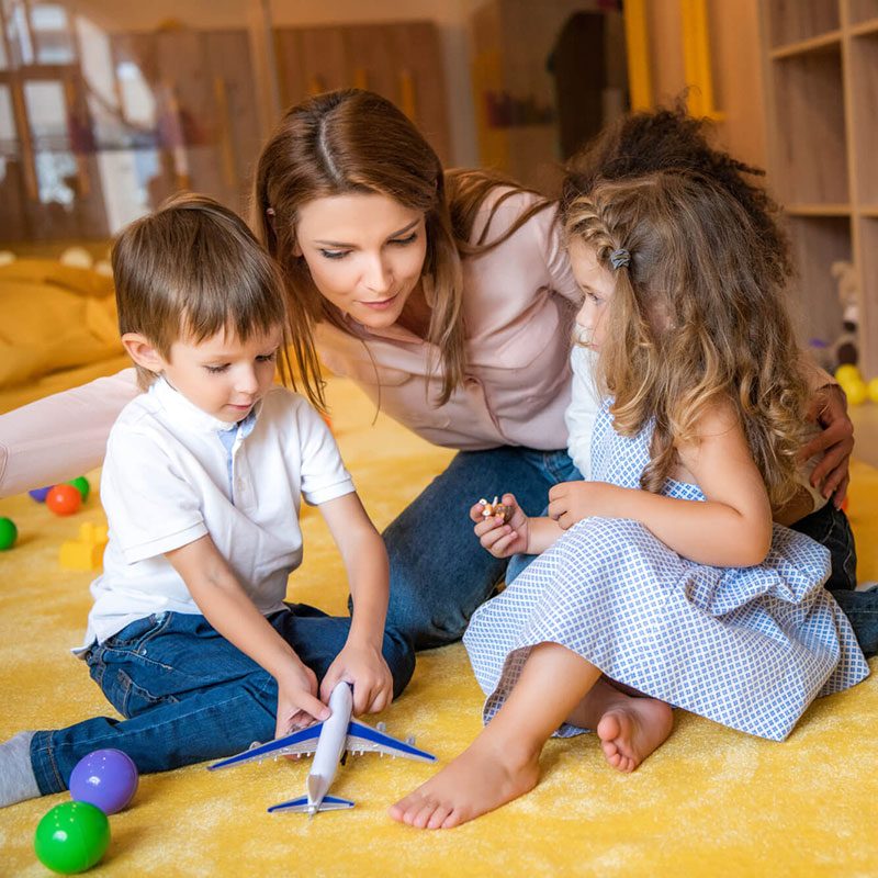 tutor-hugging-adorable-kids-on-carpet-in-kindergarten1